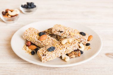 Arka planda çeşitli granola barlar var. Mısır gevreği gofretleri. Yulaf, fındık ve böğürtlenli kahvaltı barları, yakın çekim. Süper yiyecek konsepti.