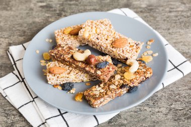 Arka planda çeşitli granola barlar var. Mısır gevreği gofretleri. Yulaf, fındık ve böğürtlenli kahvaltı barları, yakın çekim. Süper yiyecek konsepti.