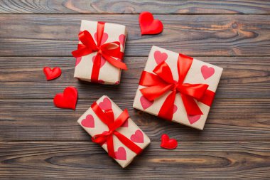 Top view photo of valentine day decorations gift box with red ribbon bow on colored background. Holiday gift boxes with top view.