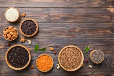 Smal Bowl 'da renkli arka planda çeşitli süper yiyecekler. Pirinç, chia, kinoa, mercimek, fındık, susam tohumu, badem gibi süper yiyecekler. üst görünüm kopyalama alanı.