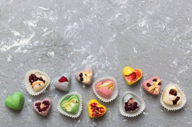 chocolate sweets in the form of a heart with fruits and nuts on a colored background. top view with space for text, holiday concept.