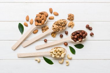 mixed nuts in white wooden spoon. Mix of various nuts on colored background. pistachios, cashews, walnuts, hazelnuts, peanuts and brazil nuts.