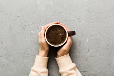 Renkli arka planda bir fincan kahve tutan minimalist stil bir kadın. Düz yerde, kapuçino bardağının üstünde. Metin için boş yer, kopyalama alanı. Kahve bağımlılığı. Üst manzara, düz uzanma.