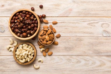 Renkli masadaki ahşap kasede fındık çeşitleri. Ceviz, fındık, ceviz, badem. Fındık Üst görünümü ile kopyalama alanını karıştır.