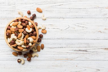 Renkli masadaki ahşap kasede fındık çeşitleri. Ceviz, fındık, ceviz, badem. Fındık Üst görünümü ile kopyalama alanını karıştır.