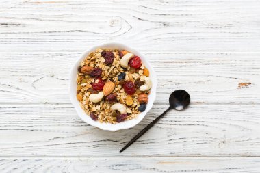 Sağlıklı bir kahvaltı hazırlıyorum. Bir kasede çeşitli kurutulmuş meyve ve fındıklı granola. Sağlıklı tatlı kavramı. Düz konum, kopyalama alanı olan üst görünüm.
