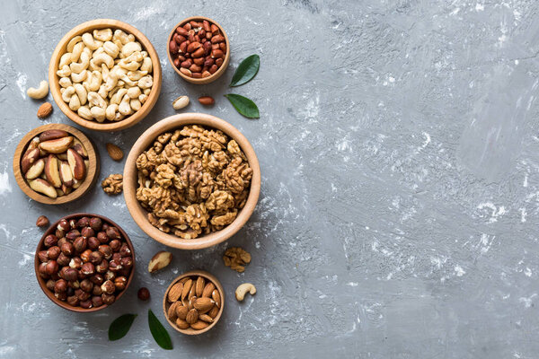 mixed nuts in wooden bowl. Mix of various nuts on colored background. pistachios, cashews, walnuts, hazelnuts, peanuts and brazil nuts.