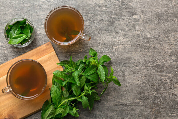 Чашка мятного чая на фоне стола. Зеленый чай со свежим мятным видом сверху с копировальным пространством.