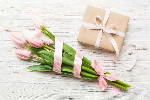 stock image Pink tulips flowers and gift or present box on colored table background. Mothers Day, Birthday, Womens Day, celebration concept. Space for text top view.