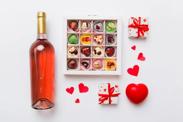 stock image Bottle of red wine on colored background for Valentine Day with gift and chocolate. Heart shaped with gift box of chocolates top view with copy space.