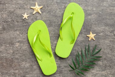 Renkli arka planda parmak arası terlikleri ve deniz kabuğu olan düz bir kompozisyon. Metin üstü görünümü için boşluk.