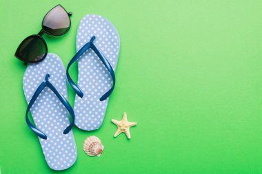 Summer travel concept. Flip flops, sunglasses and starfish on white. Top view on colored background.