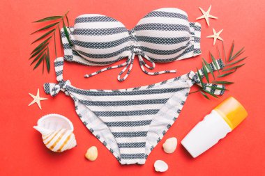 Kadın mayo ve plaj aksesuarları renkli arka plan yaz seyahati konseptine düz bir görünüm kazandırıyordu. Bikini mayo, hasır şapka ve deniz topuklu ayakkabı. Üst görünümü kopyala.