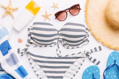 Woman swimwear and beach accessories flat lay top view on colored background Summer travel concept. bikini swimsuit, straw hat and seasheels. Copy space Top view.
