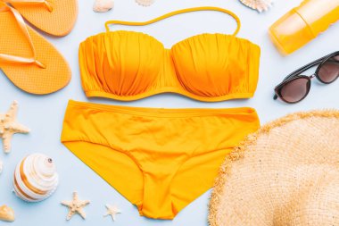 Kadın mayo ve plaj aksesuarları renkli arka plan yaz seyahati konseptine düz bir görünüm kazandırıyordu. Bikini mayo, hasır şapka ve deniz topuklu ayakkabı. Üst görünümü kopyala.