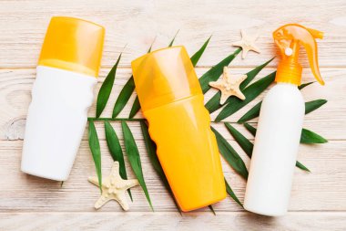 Güneş kremi şişesi. Güneş korumalı krem ve tropik yeşil yapraklı deniz kabukları olan bir şişe..