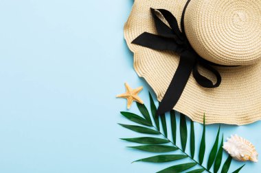 Summer holidays. Summer concept with straw hat and tropical leaf. Flat lay, top view, copy space.