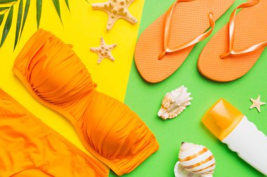 Kadın mayo ve plaj aksesuarları renkli arka plan yaz seyahati konseptine düz bir görünüm kazandırıyordu. Bikini mayo, hasır şapka ve deniz topuklu ayakkabı. Üst görünümü kopyala.