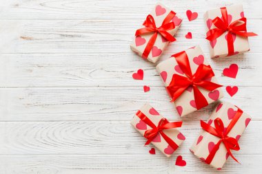 Top view photo of valentine day decorations gift box with red ribbon bow on colored background. Holiday gift boxes with top view.