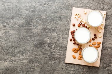 Masa arkasında çeşitli vejetaryen süt bademi, kaju fıstığı seti ya da koleksiyonu. Vejetaryen bitkisi sütü ve malzemeleri, üst görünüm.