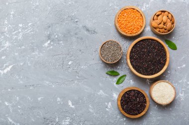 Smal Bowl 'da renkli arka planda çeşitli süper yiyecekler. Pirinç, chia, kinoa, mercimek, fındık, susam tohumu, badem gibi süper yiyecekler. üst görünüm kopyalama alanı.