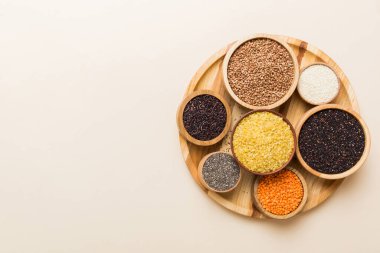 Smal Bowl 'da renkli arka planda çeşitli süper yiyecekler. Pirinç, chia, kinoa, mercimek, fındık, susam tohumu, badem gibi süper yiyecekler. en üstteki görünüm.