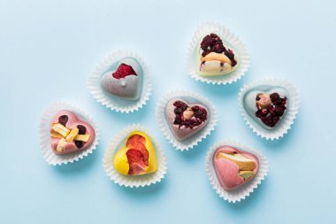 chocolate sweets in the form of a heart with fruits and nuts on a colored background. top view with space for text, holiday concept.