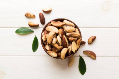 Fresh healthy Brazil nuts in bowl on colored table background. Top view Healthy eating bertholletia concept. Super foods.