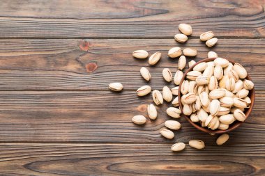 Renkli masa arkasında kasede taze ve sağlıklı Pistachio tabağı. Üst Manzara. Sağlıklı beslenme konsepti. Süper Yiyecekler.