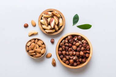 mixed nuts in wooden bowl. Mix of various nuts on colored background. pistachios, cashews, walnuts, hazelnuts, peanuts and brazil nuts.