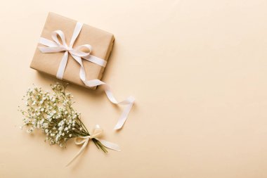 Hediye kutusu ya da hediye kutusu ve çiçek çıngıraklı yılanı ışık masasının üstünde. Tebrik kartı. Kopya alanı ile düz uzanma biçimi.