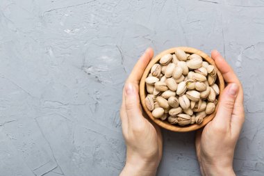 Fıstıklı ahşap bir kase tutan kadın elleri. Sağlıklı yemek ve atıştırmalık. Farklı fındıklı vejetaryen atıştırmalıkları..