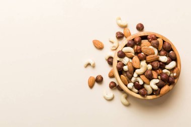 Renkli masadaki ahşap kasede fındık çeşitleri. Ceviz, fındık, ceviz, badem. Fındık Üst görünümü ile kopyalama alanını karıştır.