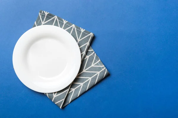 食べ物のためのテーブルクロス上の色の背景の空の丸い白いプレートの上のビュー あなたのデザインのためのスペースとナプキンに空の料理 — ストック写真