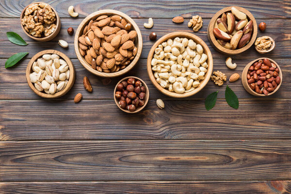 mixed nuts in wooden bowl. Mix of various nuts on colored background. pistachios, cashews, walnuts, hazelnuts, peanuts and brazil nuts.
