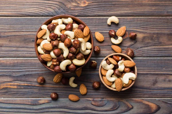 Stock image Assortment of nuts in wooden bowl on colored table. Cashew, hazelnuts, walnuts, almonds. Mix of nuts Top view with copy space.