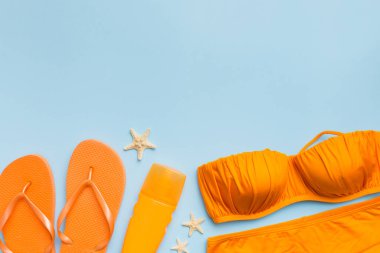 Woman swimwear and beach accessories flat lay top view on colored background Summer travel concept. bikini swimsuit, straw hat and seasheels. Copy space Top view.