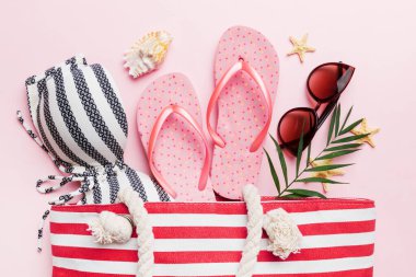 Plaj aksesuarları renkli arka plan yaz seyahati konseptinde düz bir görünüm sergiliyordu. İçinde deniz yıldızı ve deniz kabuğu olan bir çanta. Üst görünüm.