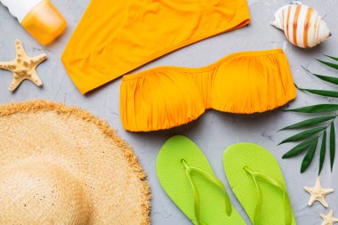 Kadın mayo ve plaj aksesuarları renkli arka plan yaz seyahati konseptine düz bir görünüm kazandırıyordu. Bikini mayo, hasır şapka ve deniz topuklu ayakkabı. Üst görünümü kopyala.