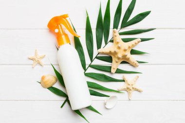 Güneş kremi şişesi. Güneş korumalı krem ve tropik yeşil yapraklı deniz kabukları olan bir şişe..