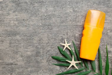 Güneş kremi şişesi. Güneş korumalı krem ve tropik yeşil yapraklı deniz kabukları olan bir şişe..