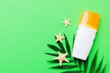 Güneş kremi şişesi. Güneş korumalı krem ve tropik yeşil yapraklı deniz kabukları olan bir şişe..