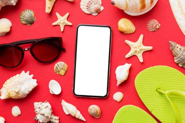 Renkli arka planda telefon ve plaj aksesuarları olan düz kompozisyon. Boş ekran ile akıllı telefon kopyalama alanı ile taklit.