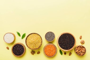 Smal Bowl 'da renkli arka planda çeşitli süper yiyecekler. Pirinç, chia, kinoa, mercimek, fındık, susam tohumu, badem gibi süper yiyecekler. üst görünüm kopyalama alanı.