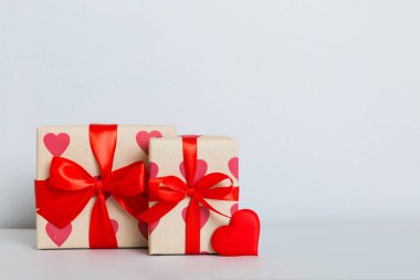 gift box with red bow and red heart on colored background. Perspective view. Flat lay.