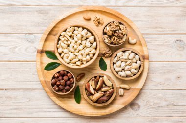 mixed nuts in wooden bowl. Mix of various nuts on colored background. pistachios, cashews, walnuts, hazelnuts, peanuts and brazil nuts.