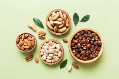 mixed nuts in wooden bowl. Mix of various nuts on colored background. pistachios, cashews, walnuts, hazelnuts, peanuts and brazil nuts.