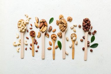 mixed nuts in white wooden spoon. Mix of various nuts on colored background. pistachios, cashews, walnuts, hazelnuts, peanuts and brazil nuts.