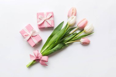 Pembe lale çiçekleri ve hediye ya da renkli masa arkaplanındaki hediye kutusu. Anneler günü, doğum günü, kadınlar günü, kutlama konsepti. Metin üstü görünümü için boşluk.