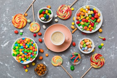 Coffee cup with chocolates and colored candy. Top view on table background with copy space.